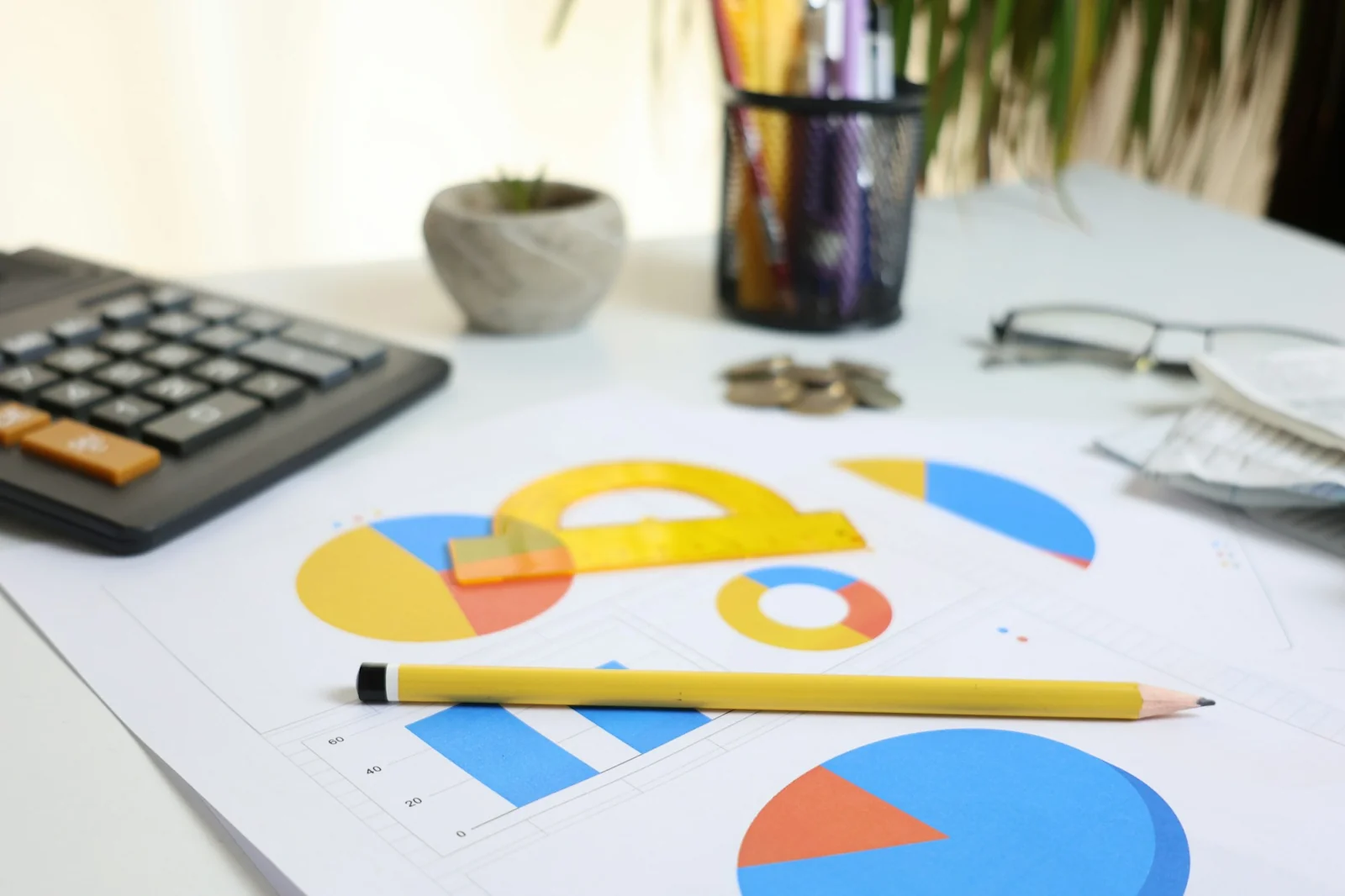 Desk with a calculator, charts and a pencil.
